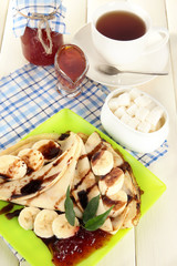 Pancakes with banana on plate on wooden background