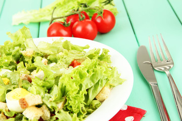 Caesar salad on blue plate, on color wooden background