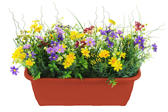 Composition of artificial garden flowers in brown flowerpot isol