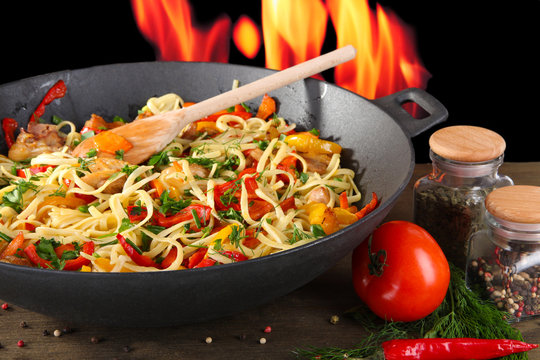 Noodles With Vegetables On Wok On Fire Background