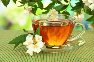 Cup of tea with jasmine, on bamboo mat, on bright background