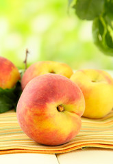 Ripe sweet peaches on wooden table in garden, close up