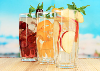 Glasses of fruit drinks with ice cubes on blue background