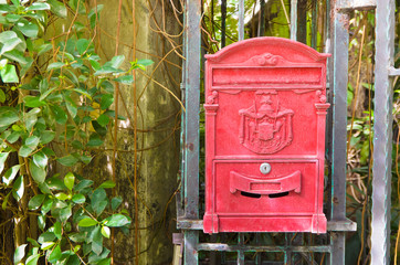 Traditional old English red postbox hang on gate