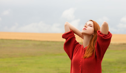 Redhead girl at meadow near wheat field