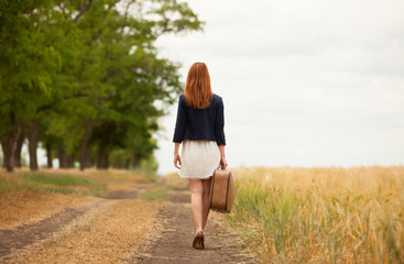 Redhead girl with suitcase at outdoor.
