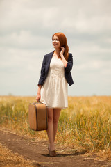 Redhead girl with suitcase at outdoor.