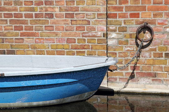 Ein blaues Ruderboot an einer Wand angedockt