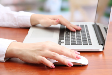 Female hands working on laptop, on bright background