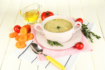 Nourishing soup in pink pan on wooden table close-up