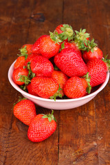 Fresh strawberry in bowl on wooden background
