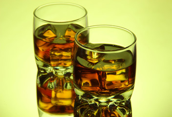 Brandy glasses with ice on green background