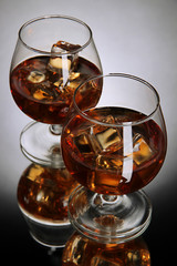 Brandy glasses with ice on grey background