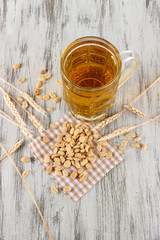 Fototapeta na wymiar Beer in glass and nuts on napkin on wooden table
