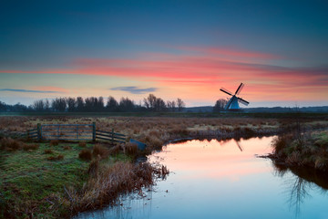 pink sunrise over Dutch windmill and river