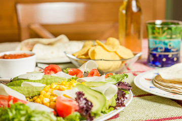Traditional mexican food with a plate of fresh salad, tortillas,