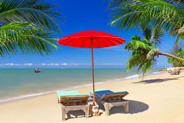Tropical beach scenery with parasol and deck chairs in Thailand
