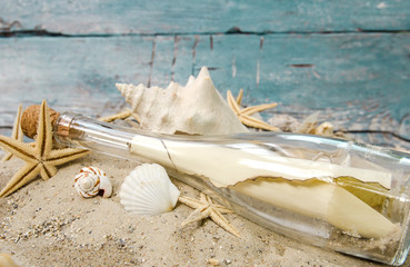 Strandgut: Flaschenpost mit Muscheln und Sand