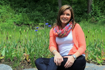 Pretty young woman sitting on rock in garden