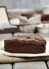 Chocolate cake on white plate, on hessian. Coffee beans on woode