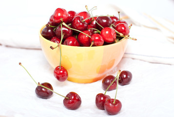 Obraz na płótnie Canvas ripe cherries in a yellow plate