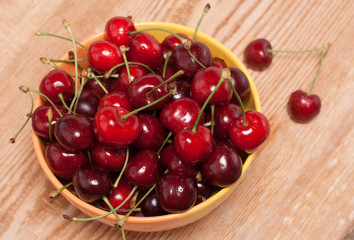 ripe cherries in a yellow bowl, top view