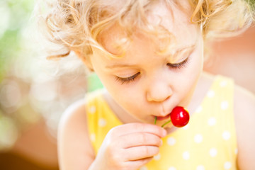 Little Girl eats sweet cherries outdoor