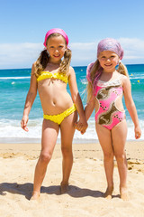 Two girls in swimwear on beach.