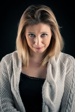 Sad blonde woman close up portrait on dark background.