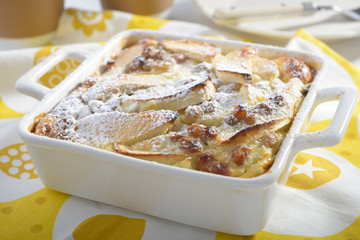 Apple flognarde with raisins and powdered sugar in a baking dish