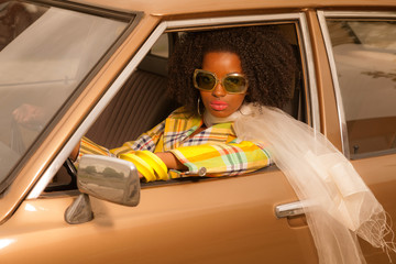 Vintage 70s fashion afro woman with sunglasses driving in brown