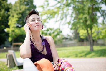 beautiful hipster short hair woman listening music in the park