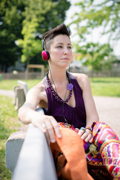 beautiful hipster short hair woman listening music in the park