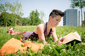 Naklejka na ściany i meble beautiful hipster short hair woman reading book in the park