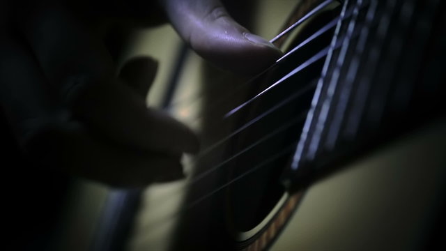 Fingers on the chords of a guitar