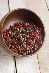 Mixed pepper in wooden can on wooden background