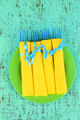 Blue plastic forks wrapped in yellow paper napkins,