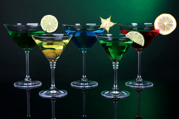 Alcoholic cocktails in martini glasses on dark green background