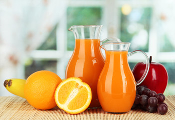 Orange juice in pitchers on table in room