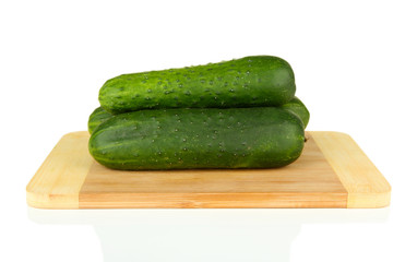 Tasty green cucumbers on wooden cutting board, isolated on