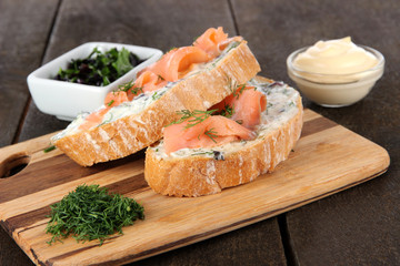 Fish sandwiches on cutting board on wooden table