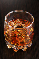 Brandy glass with ice on wooden background