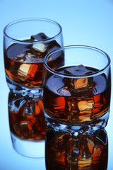 Brandy glasses with ice on blue background