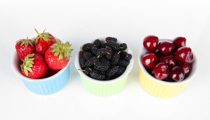 Ripe mulberries with cherry and strawberries in bowls isolated
