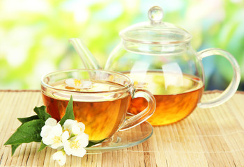Cup of tea with jasmine, on bamboo mat, on bright background