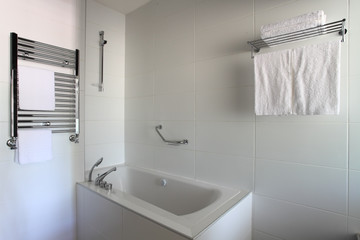 Fototapeta na wymiar Bathtub, heated towel rail and shelf in bathroom.
