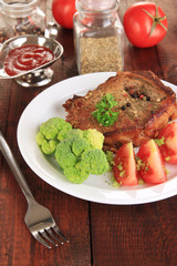 Piece of fried meat on plate on wooden table close-up