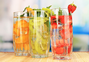 Glasses of fruit drinks with ice cubes on table in cafe