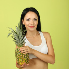 Girl with fresh pineapple on green background