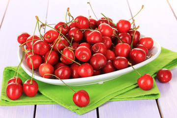 Cherry berries in bowl on wooden table close up